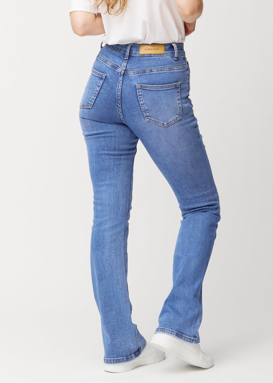 Blå mid-rise bootcutjeans i färgen Rivers. Bakifrån på en modell, så att hela passformen syns.