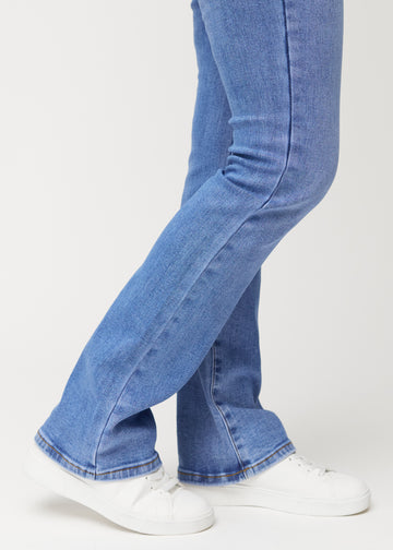 Blå mid-rise bootcutjeans i färgen Rivers. Närbild vid ankeln på en modell som visar den lätta utsvängningen nedtill.