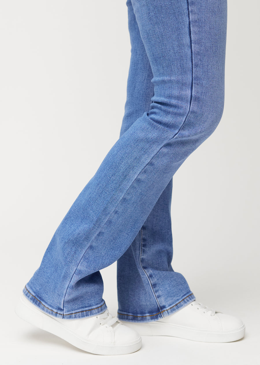 Blå mid-rise bootcutjeans i färgen Rivers. Närbild vid ankeln på en modell som visar den lätta utsvängningen nedtill.