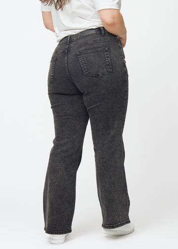 Mörkgrå mid-rise bootcutjeans i färgen Shadows. Bakifrån på en plus size-modell, så att hela passformen syns.