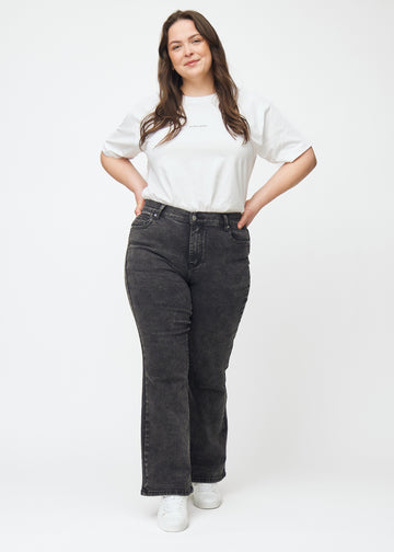 Mörkgrå mid-rise bootcutjeans i färgen Shadows. Helbild av en plus size-modell i jeansen.