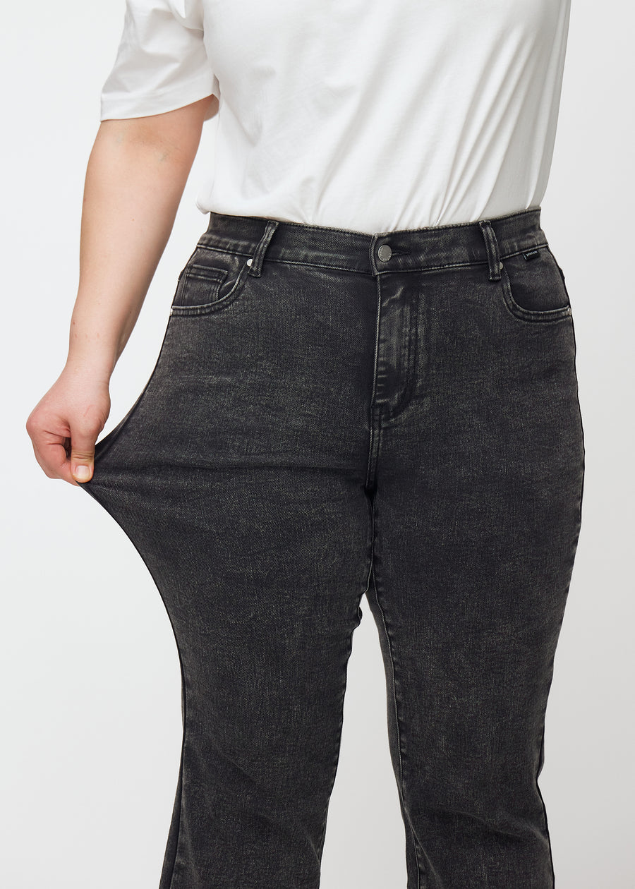 Mörkgrå mid-rise bootcutjeans i färgen Shadows. En plus size-modell drar i jeanstyget vid låret för att visa stretchen.