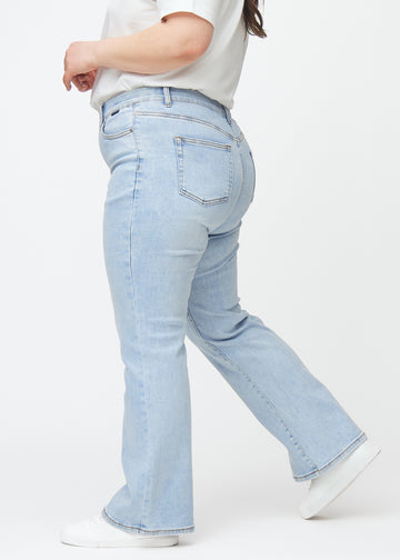 Ljusblå mid-rise bootcutjeans i färgen Waves. Från sidan på en plus size-modell.