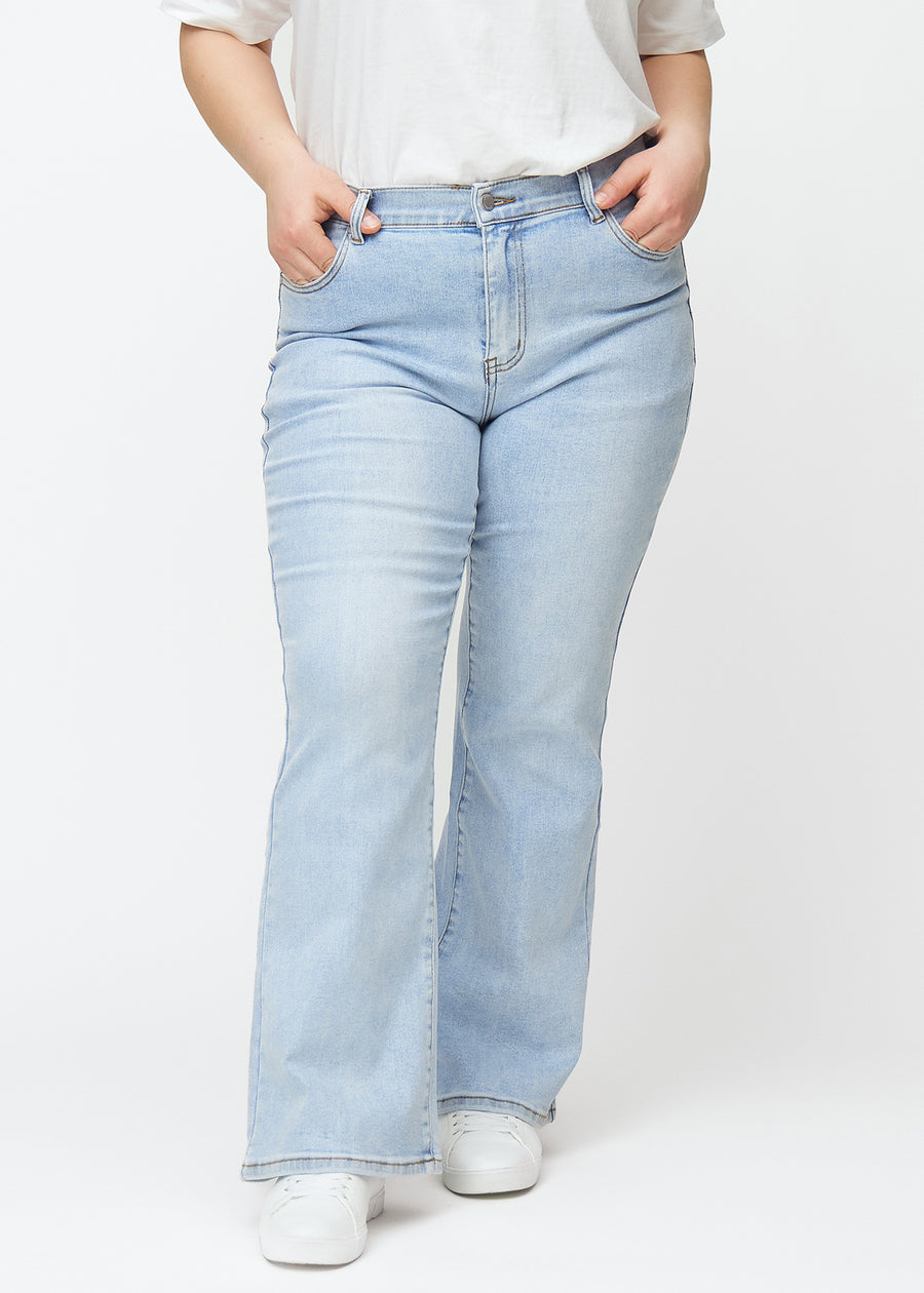 Ljusblå mid-rise bootcutjeans i färgen Waves. Framifrån på en plus size-modell, med nära passform över höfter och lår och lätt utsvängning nedtill.