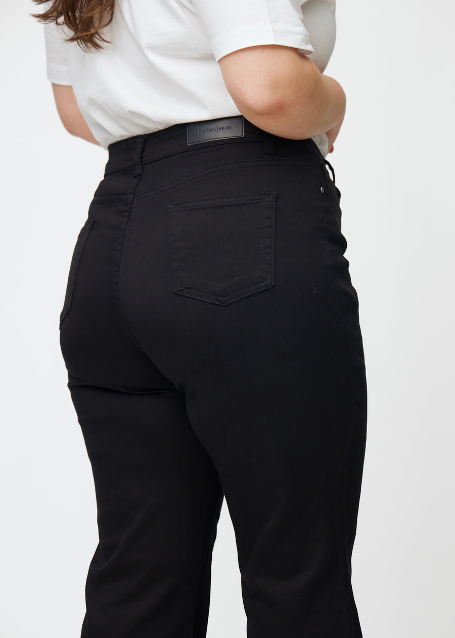 Svarta högmidjade bootcut jeans sedda bakifrån i närbild på en plus size-modell för att visa detaljer.