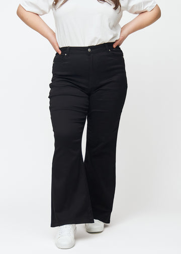 Svarta högmidjade bootcut jeans, modellnamn Ravens, som sitter tajt från midja till lår och har en lätt vidd nedtill, på en plus size-modell, sett framifrån.