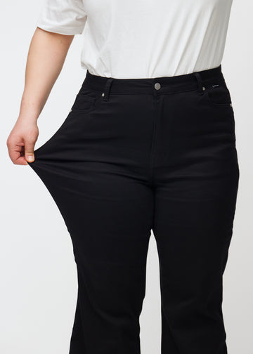 Plus size-modellen stretchar jeansen vid låret för att visa stretchen.