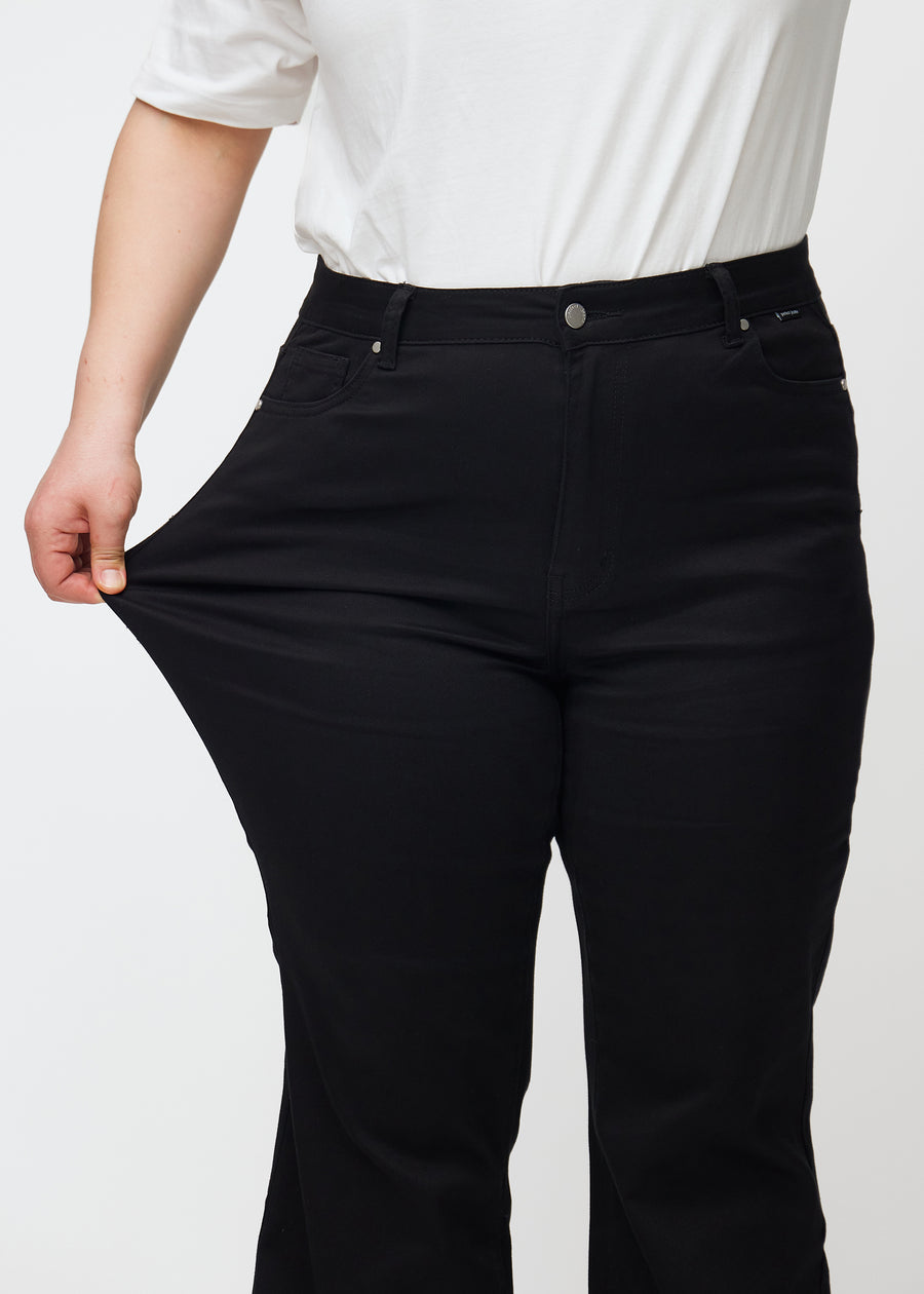 Plus size-modellen stretchar jeansen vid låret för att visa stretchen.