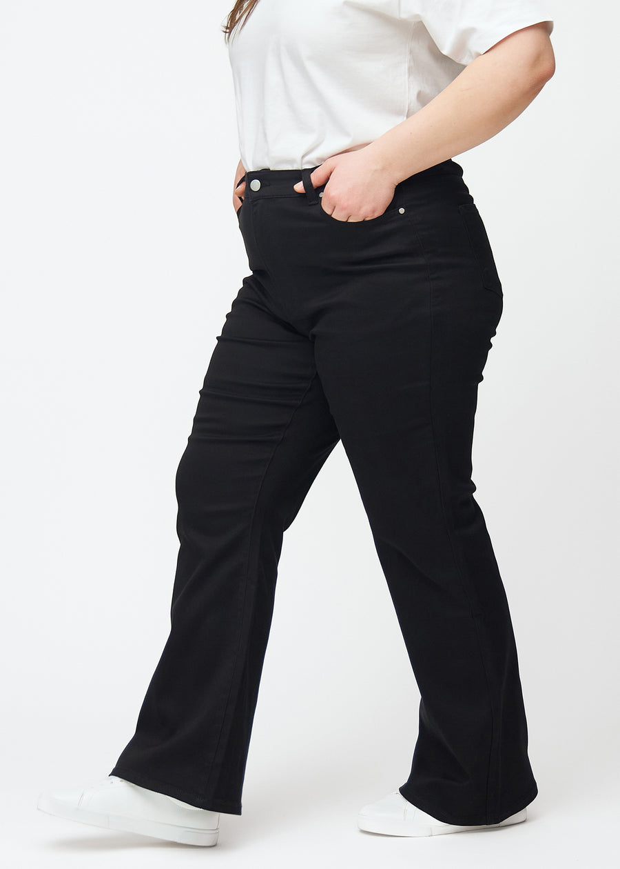 Svarta högmidjade bootcut jeans sedda från sidan på en plus size-modell.