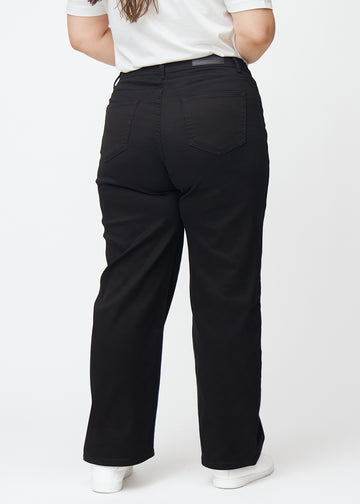 Svarta högmidjade jeans, som sitter åt i midjan och har en lös passform med vidd nedtill, sedda bakifrån på en plus-size-modell så att man kan se hela produkten.