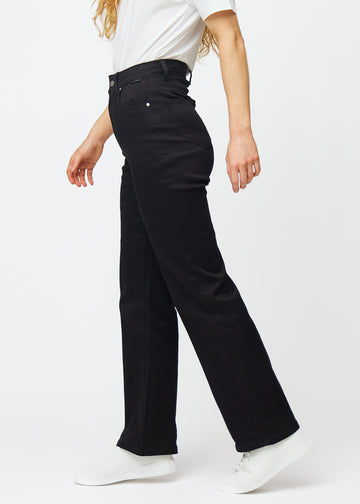 Svarta högmidjade jeans, som sitter åt i midjan och har en lös passform med vidd nedtill, sedda från sidan på en modell.