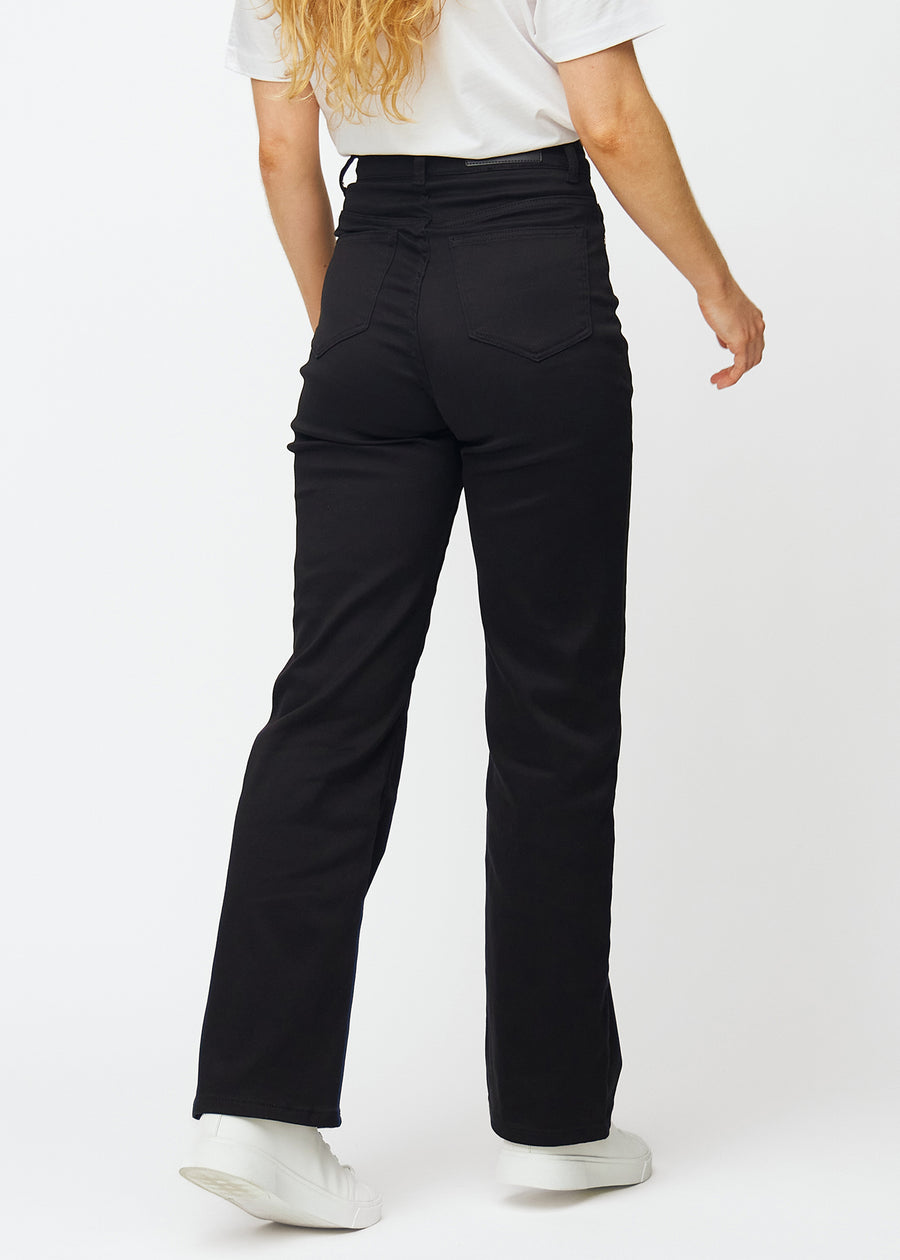 Svarta högmidjade jeans, som sitter åt i midjan och har en lös passform med vidd nedtill, sedda bakifrån för att visa hela produkten.