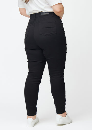 Svarta plus size jeans med hög midja i färgen Ravens med skinny fit ses bakifrån på en modell.