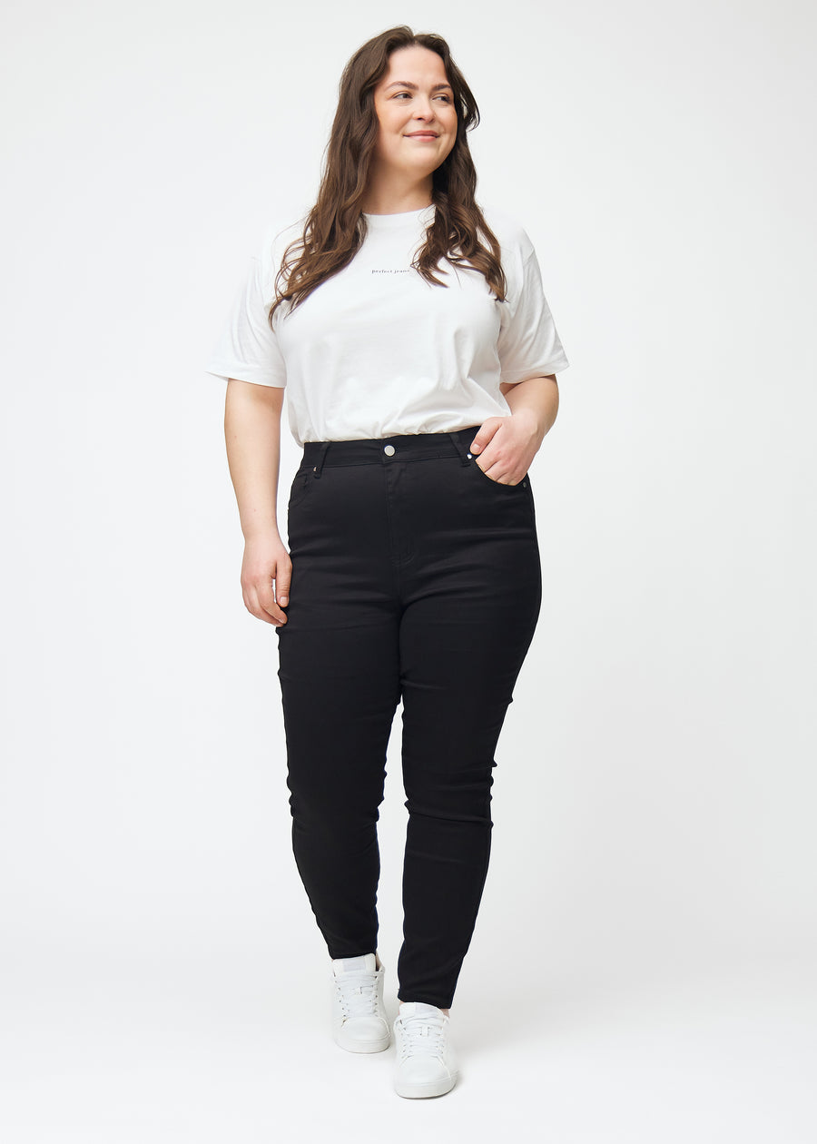 Detta är en helbild av en plus size-modell iklädd svarta high rise skinny jeans för kvinnor i färgen Ravens.