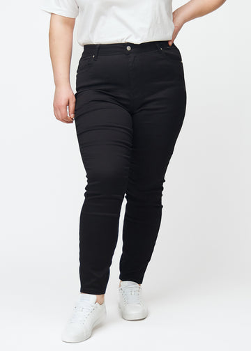 En plus size-modell visar svarta high rise skinny jeans för kvinnor i färgen Ravens sedda framifrån.