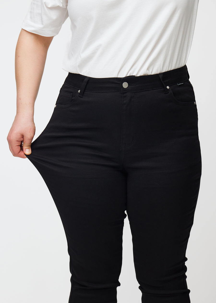 En plus size-modell sträcker de svarta stretch jeans med hög midja i färgen Ravens.