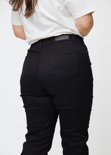 Svarta högmidjade slim jeans sedda bakifrån i närbild på en plus-size-modell för att visa detaljer.