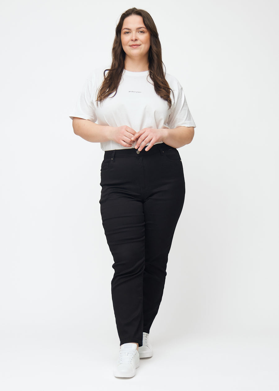 Helbild av en plus-size-modell i svarta högmidjade slim jeans.