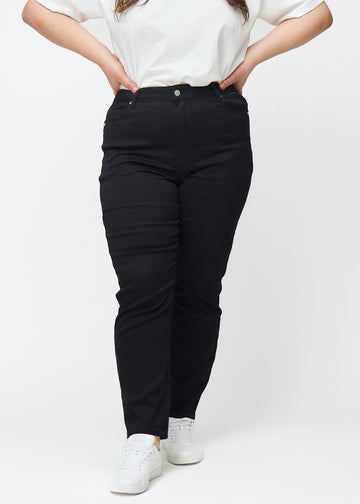 Svarta högmidjade slim jeans, modellnamn Ravens, som sitter tight längs benet, men lite lösare vid ankeln, på en plus-size-modell, sett framifrån.