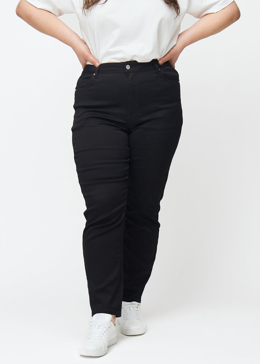 Svarta högmidjade slim jeans, modellnamn Ravens, som sitter tight längs benet, men lite lösare vid ankeln, på en plus-size-modell, sett framifrån.