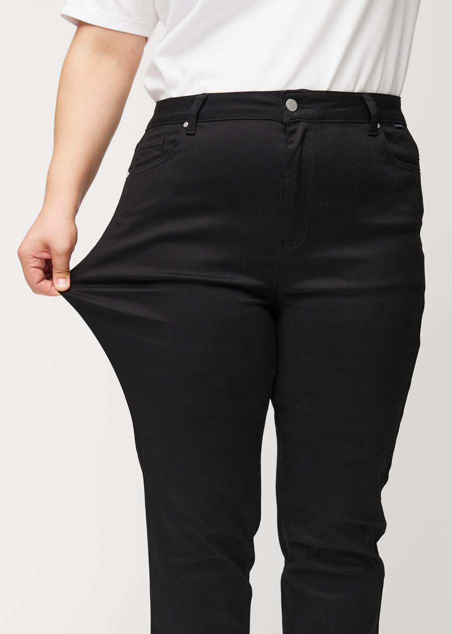 Plus-size-modellen sträcker ut jeansen vid låret för att visa stretch.