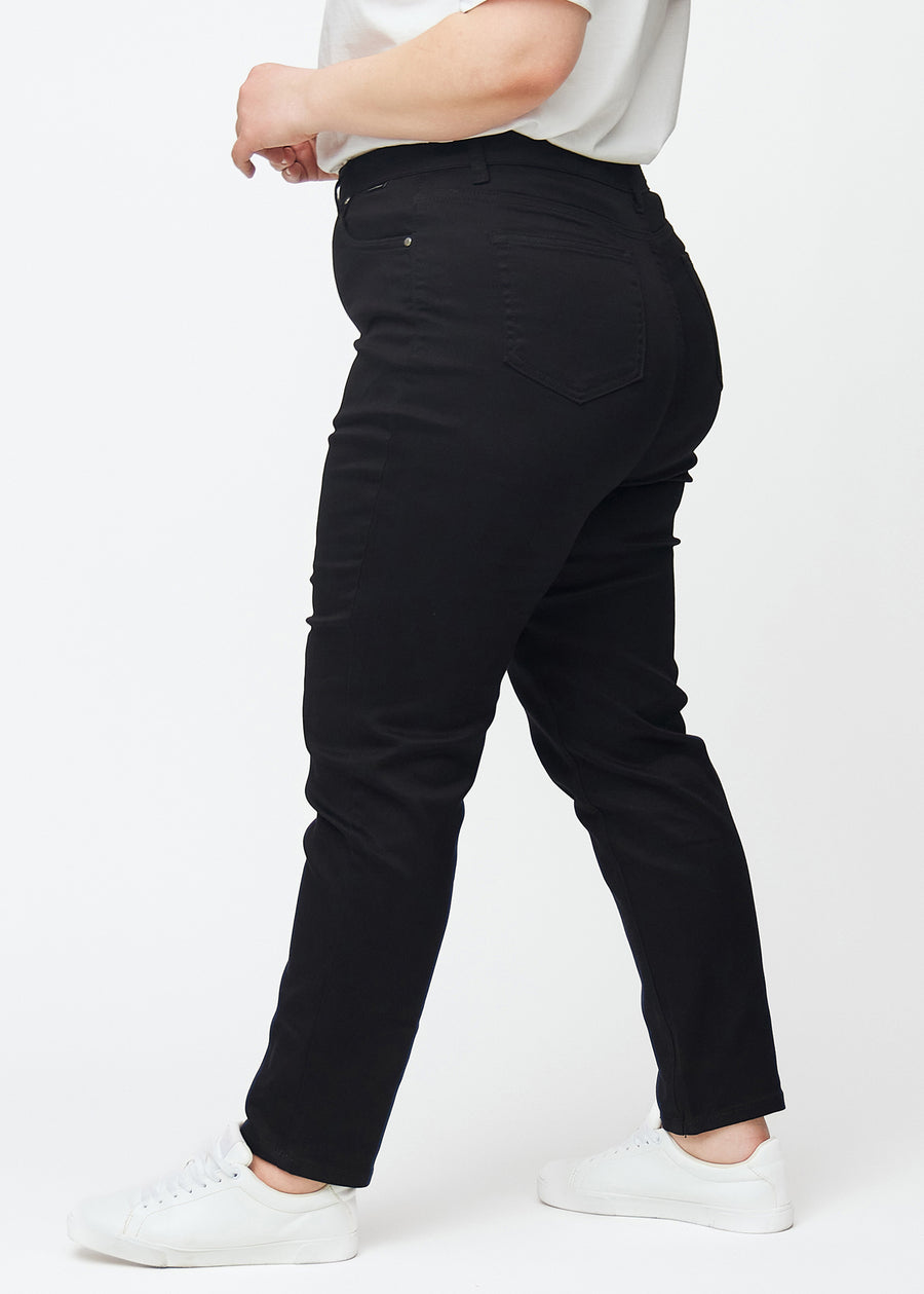 Svarta högmidjade slim jeans sedda från sidan på en plus-size-modell.
