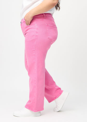 Ljusrosa loose jeans sedda från sidan på en plus size-modell.