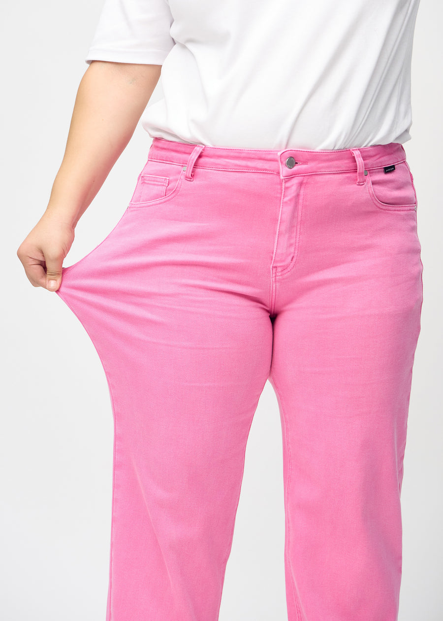 Plus size-modellen drar ut jeansen vid låret för att visa stretch.
