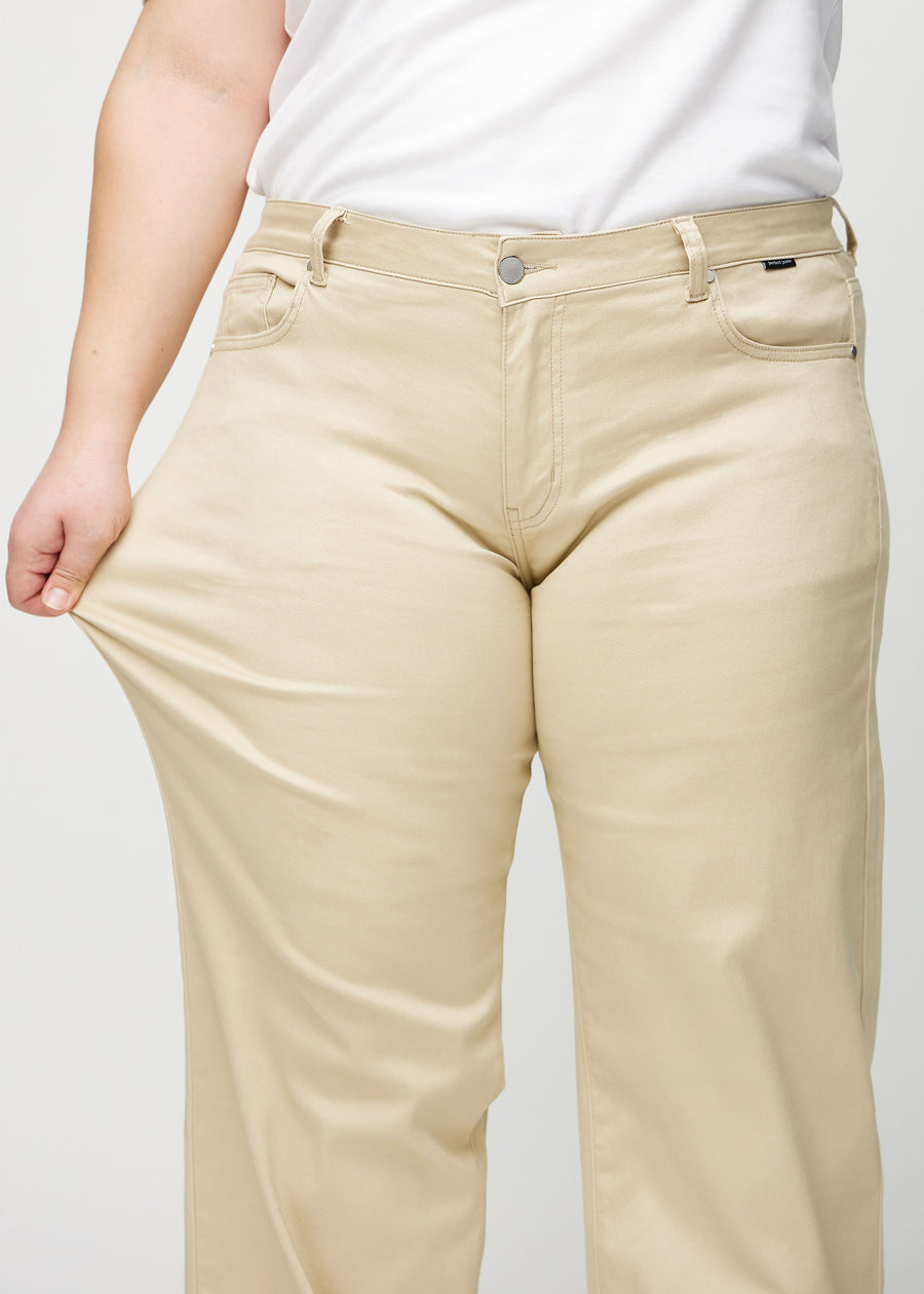 Loose jeans för kvinnor i beige, färgen Gazelles. En plus size-modell drar i jeanstyget vid låret för att visa stretchen.