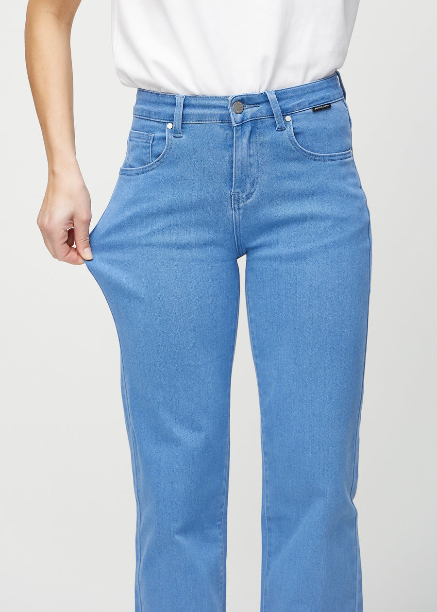 Loose jeans för kvinnor i blå, färgen Geraniums. En modell drar i jeanstyget vid låret för att visa stretchen.