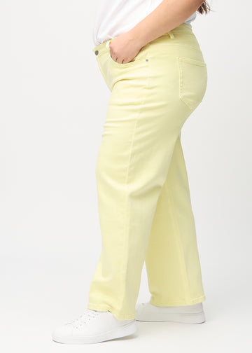 Loose jeans för kvinnor i ljusgul, färgen Lemonades. Från sidan på en plus size-modell, med synlig lös passform.