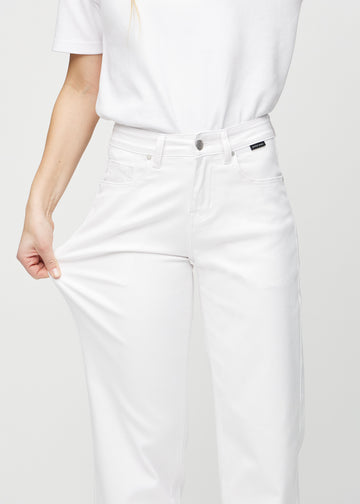 Loose jeans för kvinnor i vit, färgen Marguerites. En modell drar i jeanstyget vid låret för att visa stretchen.