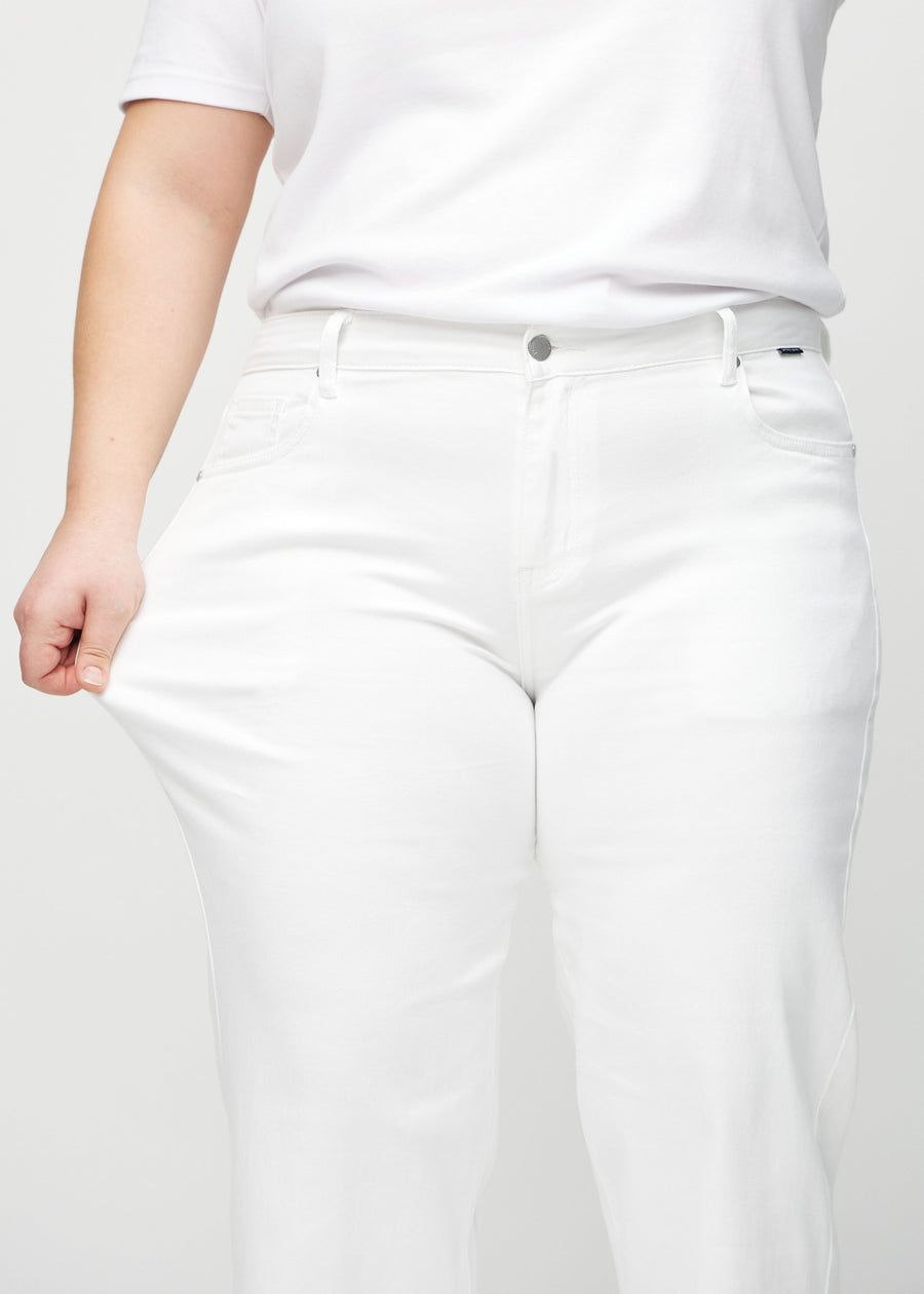 Loose jeans för kvinnor i vit, färgen Marguerites. En plus size-modell drar i jeanstyget vid låret för att visa stretchen.