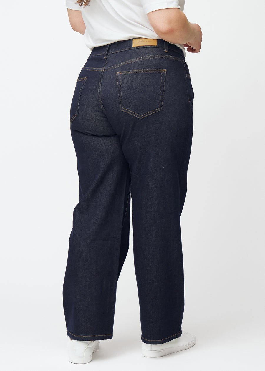 Djupt mörkblå denim jeans för kvinnor i färgen Midnights sedd bakifrån på plus-size-modell.