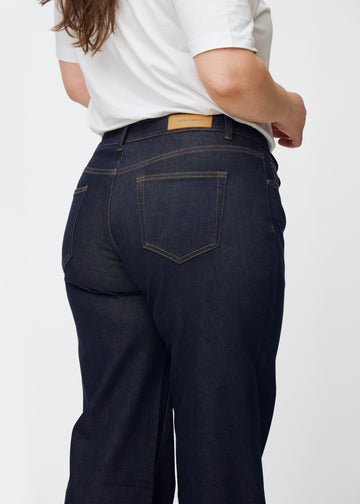 Djupt mörkblå denim jeans för kvinnor i färgen Midnights sedd bakifrån i närbild på plus-size-modell.