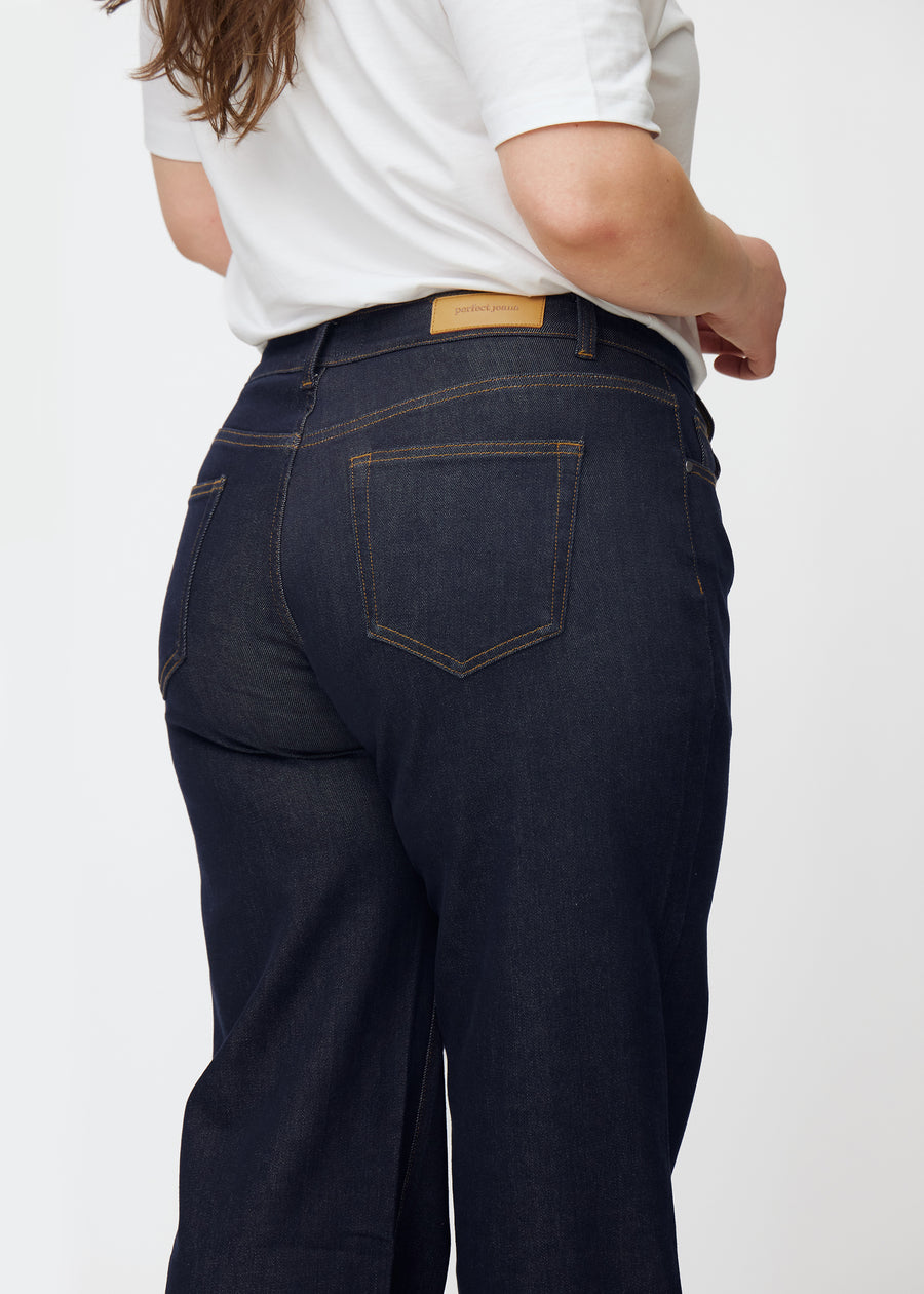 Djupt mörkblå denim jeans för kvinnor i färgen Midnights sedd bakifrån i närbild på plus-size-modell.