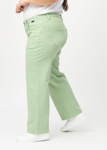 Loose jeans för kvinnor i ljusgrön, färgen Mints. Från sidan på en plus size-modell, med synlig lös passform.