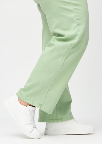 Loose jeans för kvinnor i ljusgrön, färgen Mints. Närbild vid anklarna på en plus size-modell, som visar de vida bensluten.