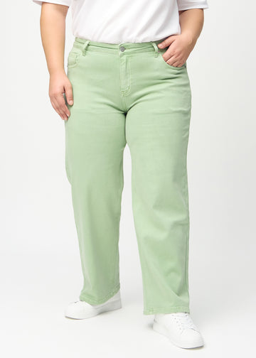 Loose jeans för kvinnor i ljusgrön, färgen Mints. Framifrån på en plus size-modell, med rymlig passform och vida ben.