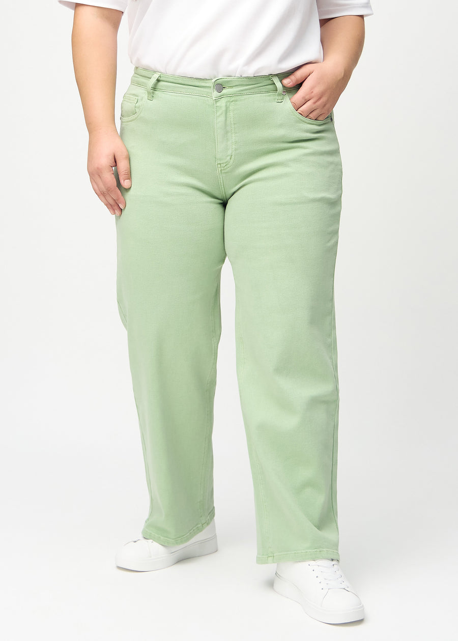 Loose jeans för kvinnor i ljusgrön, färgen Mints. Framifrån på en plus size-modell, med rymlig passform och vida ben.