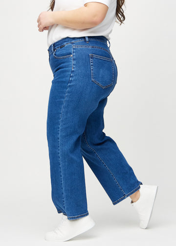 Loose jeans för kvinnor i mörkblå, färgen Oceans. Från sidan på en plus size-modell, med synlig lös passform.