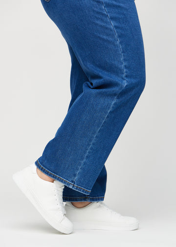 Loose jeans för kvinnor i mörkblå, färgen Oceans. Närbild vid anklarna på en plus size-modell, som visar de vida bensluten.