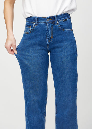Loose jeans för kvinnor i mörkblå, färgen Oceans. En modell drar i jeanstyget vid låret för att visa stretchen.
