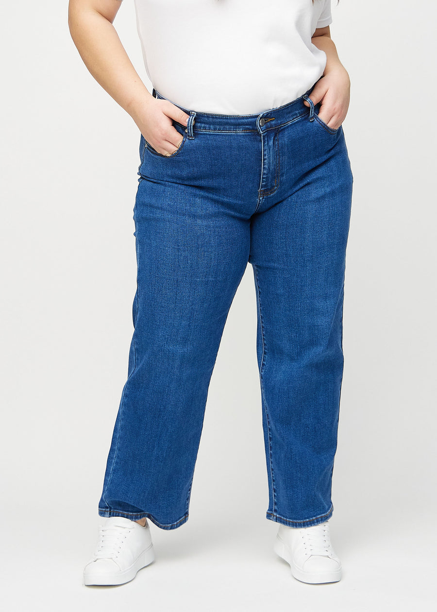 Loose jeans för kvinnor i mörkblå, färgen Oceans. Framifrån på en plus size-modell, med rymlig passform och vida ben.