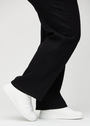 En plus-size-modells anklar, så att man kan se hur löst jeansen sitter i en Loose passform.