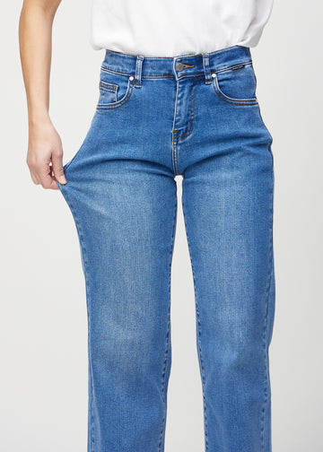 Loose jeans för kvinnor i blå, färgen Rivers. En modell drar i jeanstyget vid låret för att visa stretchen.