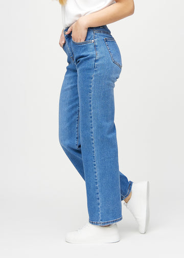 Loose jeans för kvinnor i blå, färgen Rivers. Från sidan på en modell, med synlig lös passform.