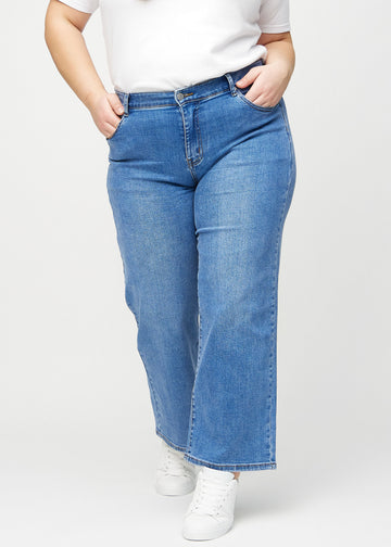 Loose jeans för kvinnor i blå, färgen Rivers. Framifrån på en plus size-modell, med rymlig passform och vida ben.