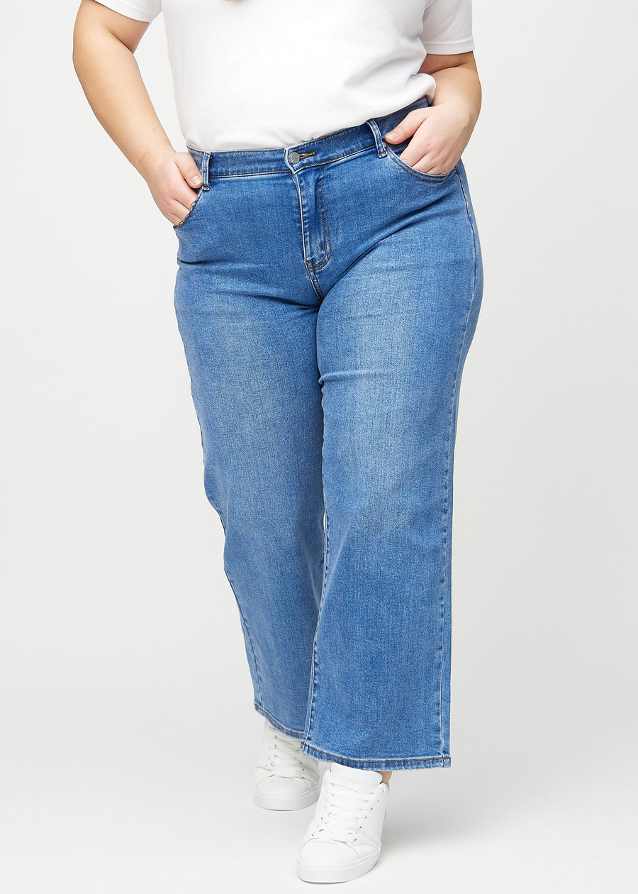Loose jeans för kvinnor i blå, färgen Rivers. Framifrån på en plus size-modell, med rymlig passform och vida ben.