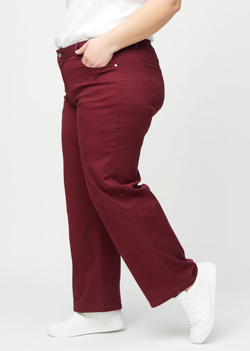 Loose jeans för kvinnor i mörkröd, färgen Santas. Från sidan på en plus size-modell, med synlig lös passform.